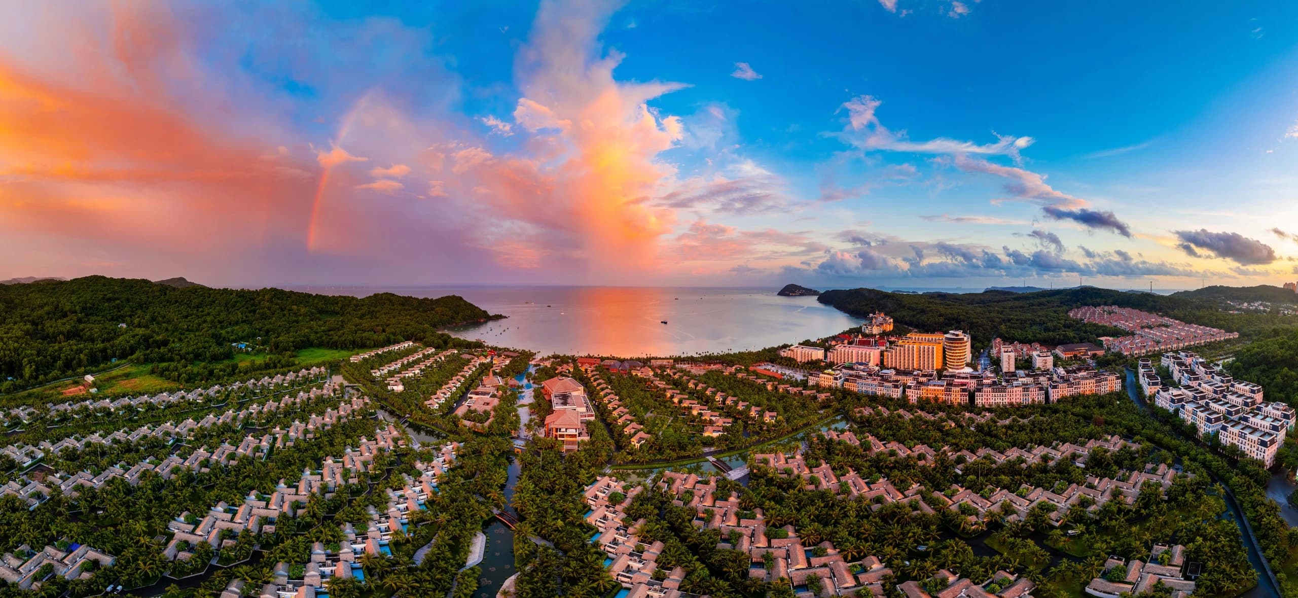 Resort buildings and greenery surrounding Khem Beach under a colourful sky