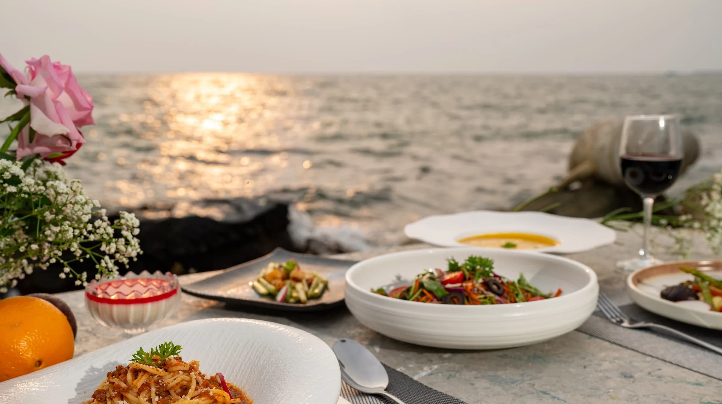 A table of prepared dishes beside the sea at sunset