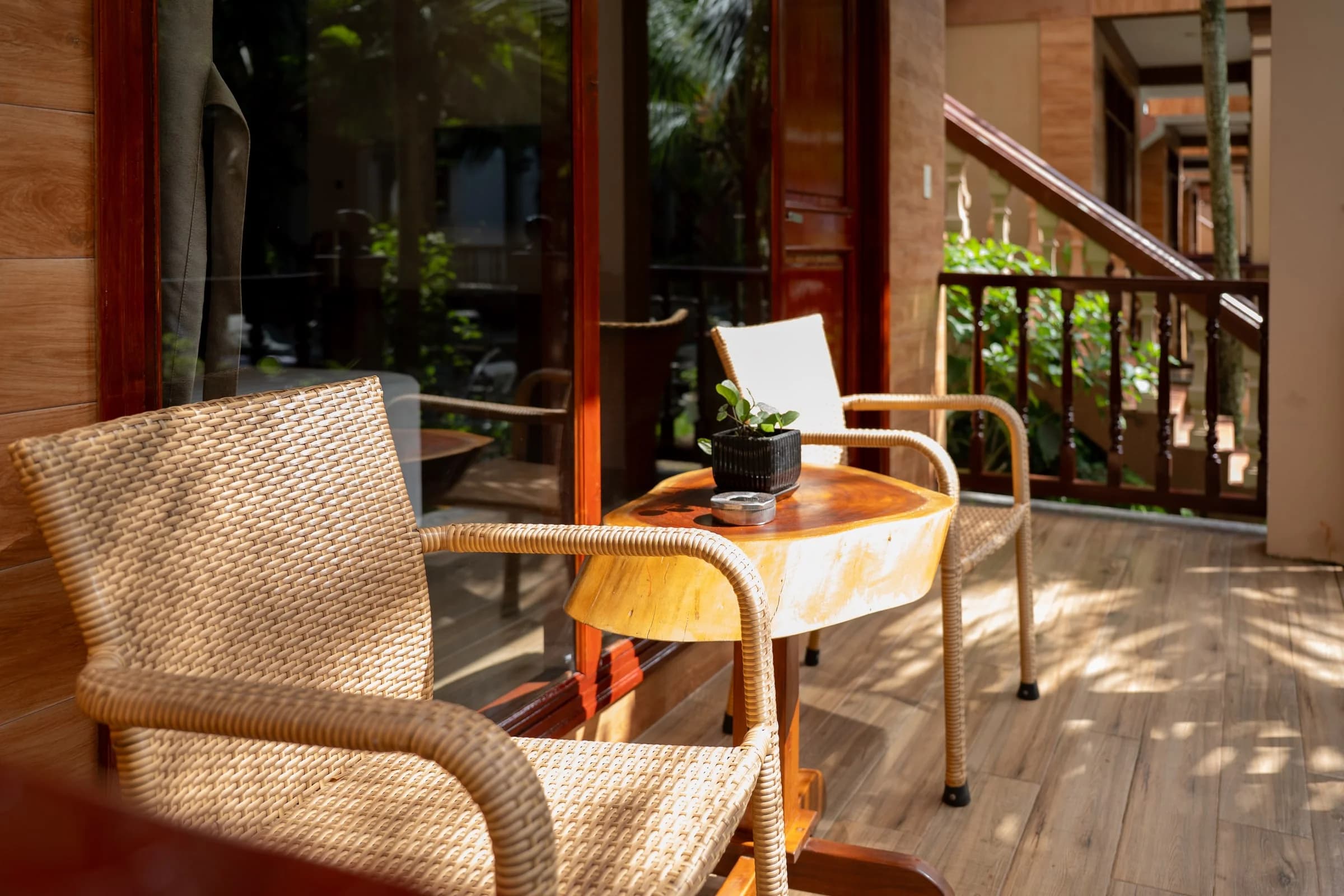 Woven chairs and a small table on a shaded wooden veranda