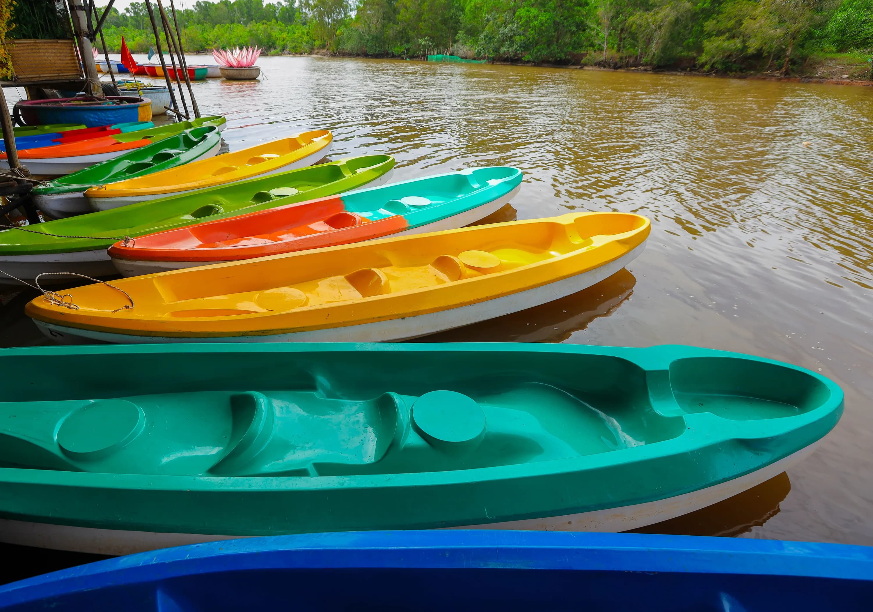 Empty single and tandem kayaks moored beside Cua Can River