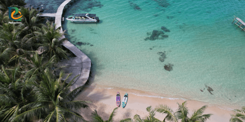 Wooden pier curving over turquoise water at Hon May Rut Trong Island in Phu Quoc