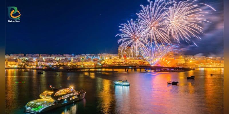 Fireworks over Kiss Bridge at Sunset Town Phu Quoc with city lights reflecting on the sea at night