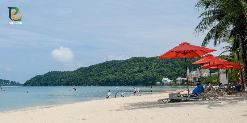 Beachfront dining setup with red umbrellas and lounge chairs on Khem Beach