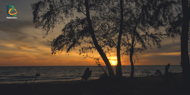 Sunset at Truong Beach Phu Quoc with silhouettes of trees and people watching the ocean