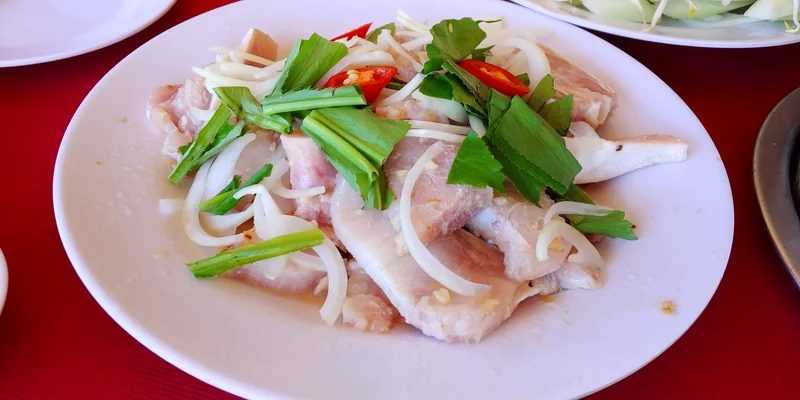 A plate of fish salad with sliced onion and herbs